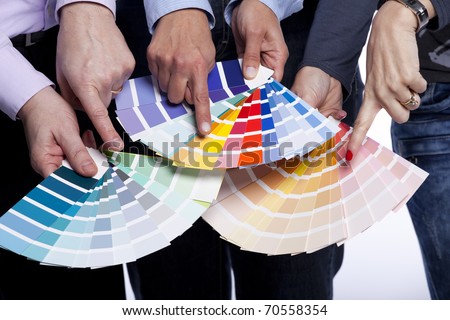 Group of people hands pointing to color samples in palette pantone (selective focus)