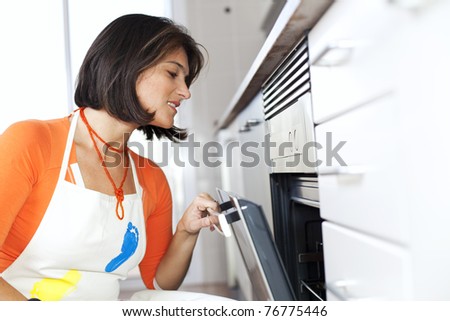 modern woman looking inside the kitchen oven