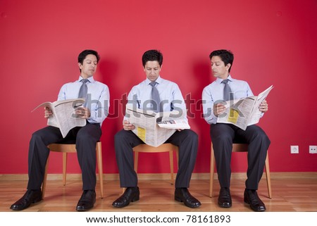 Three businessman peeking and reading the newspaper siting on a chair