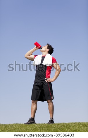 man drinking water from a bottle in a park