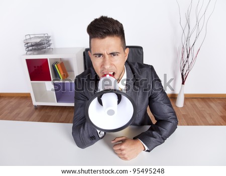 Handsome businessman at his office screaming over the megaphone