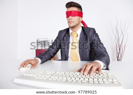 Businessman at his office with scarf covering his eyes while working with his computer