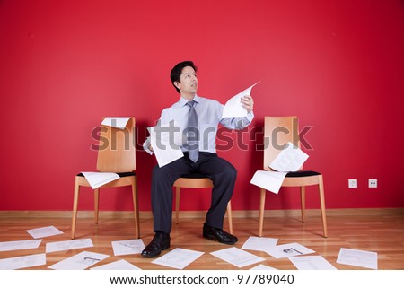 Businessman reading a document in a messy office full of papers on the floor