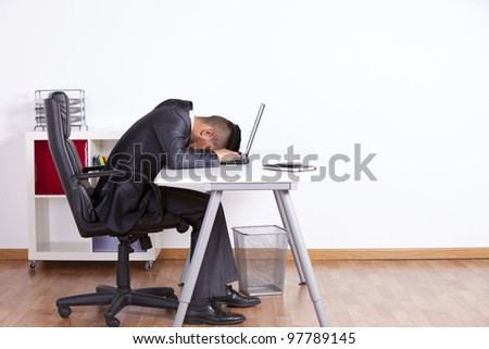 Tired businessman sleeping over his laptop at the office
