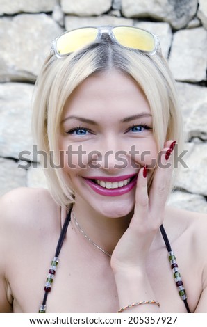 woman in a bikini smiles on the background of a stone wall