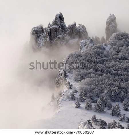 Snowy mountains with trees and fog.