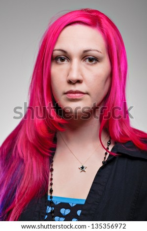 A young Caucasian woman with fuchsia colored hair with an excited expression