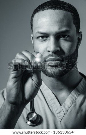 Studio shot of a young African American doctor shining a lighting instrument into your eyes.