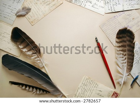 Feathers, old postcards and vintage pen around beige background