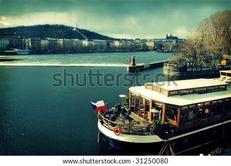 Prague view with boat on Vltava river, cross-processed photo