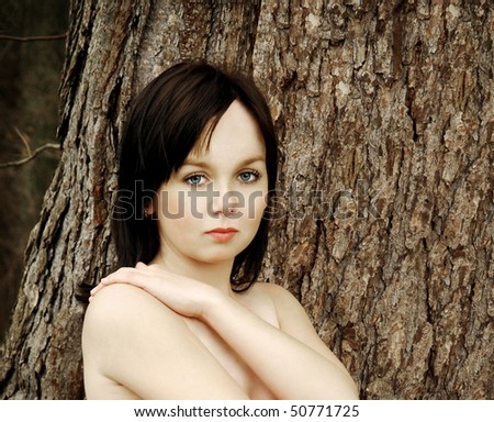 Portrait of naturally attractive girl with fair youthful skin in opposite of old tree bark