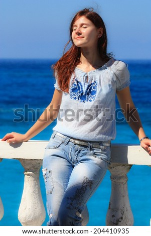 young woman enjoying the sun on her face at the sea side