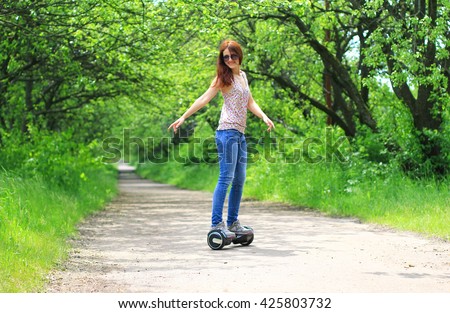 happy young woman riding a gyro scooter in the park - eco transport, hoverboard, smart balance wheel