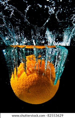 An orange in water with splash on black background