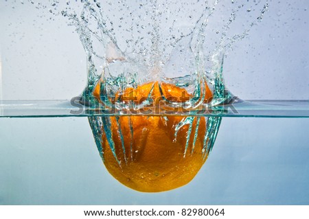 whole orange drop into water with splash