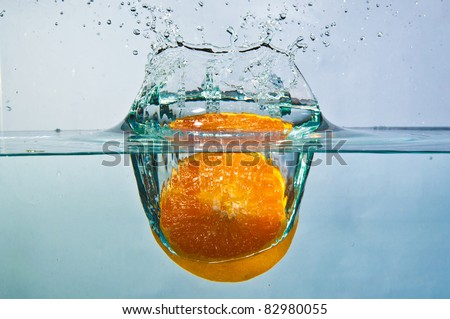 half cut orange drop into water with splash