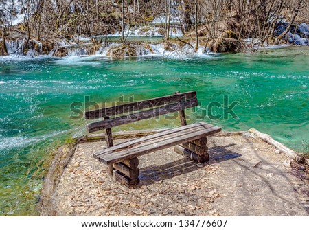 Bench surrounded by water and vegetation just before it begin to rebuild after long winter. Plitvice lakes national park in Croatia.