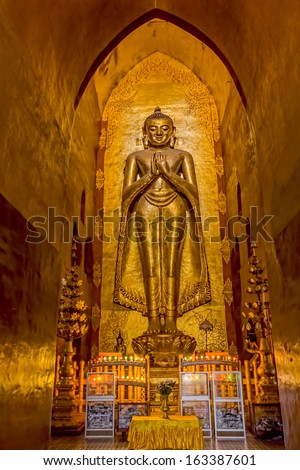 BAGAN, MYANMAR - FEBRUARY 23: Standing Buddha Kassapa at south facing part of the Ananda temple adorned by believers by sticking golden leaves on statue on February 23, 2013 in Bagan, Myanmar.