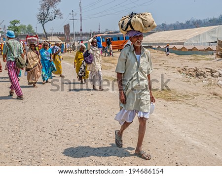 HARIDWAR, INDIA - APRIL 14, 2010: People passing carrying heavy bags at the Kumbh Mela, a mass Hindu pilgrimage of faith.