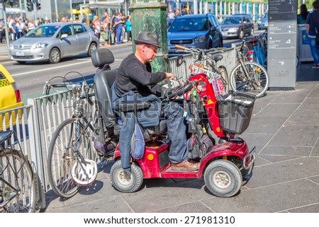 MELBOURNE, AUSTRALIA - MARCH 21, 2015: A man sitting in a vehicle for people with special needs and sells small religious booklet in front of Flinders Street Station.
