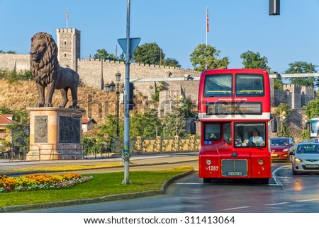 SKOPJE, MACEDONIA - JULY 17, 2015: Double decker red bus passes by the city\'s landmarks.