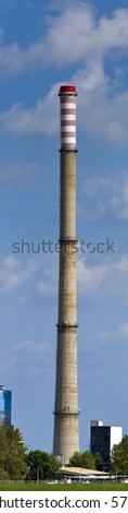 Heating and power plant near river against blue sky and green plants