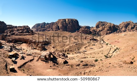 Jordan Petra desert panorama with a toms in the distance and blue sky above. Temple and tombs visible