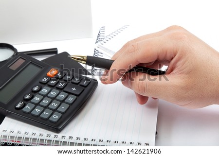 Hands holding the pen over documents and calculator.