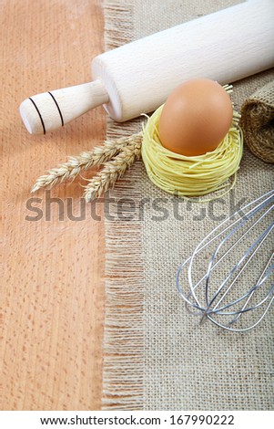 Supplies and ingredients for baking or making pasta on a wooden table.