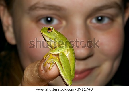 look at this a teenage girl holds up a green tree frogon the end of her finger