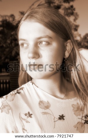 diffused sepia image of teenage girl or young woman looks off wistfully