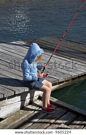 a little girl sits on the dock and goes fishing
