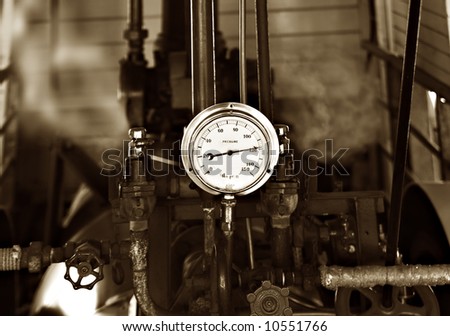 sepia image of machinery under pressure gauge lets out steam
