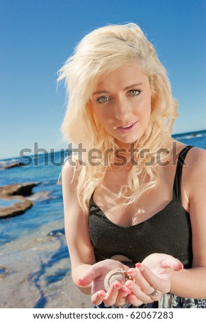 beautiful young woman collects shells at the sea