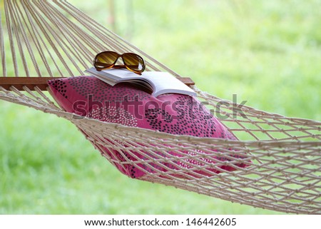 Hammock, book, pillow, and glasses on a sunny summer day