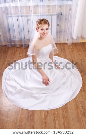 Young happy bride laughs while sitting on the floor in the house