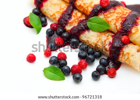 pancakes rolled in a tube with berries, filled with berry sauce on a white background