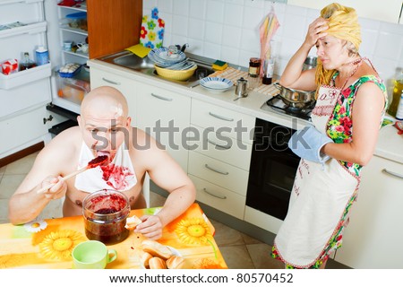 Family affair Mother and son at the kitchen he  eating sweet jam and mother looking at him disappointed
