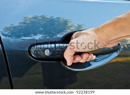 a hand is going to pull a car\'s door handle