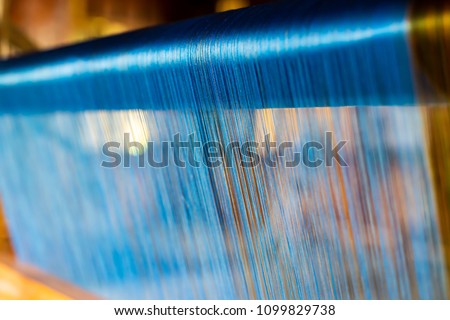 Close Up of Blue Silk on the Weaving machine and Thai traditional Silk. Weaving loom for homemade Silk textile production in Thailand