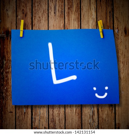 note paper and clothes peg on a wooden background with alphabet