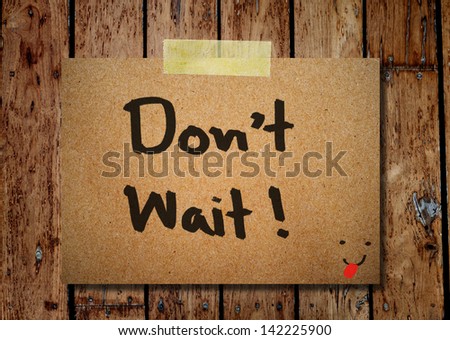 note paper and clothes peg on a wooden background with do no wait message