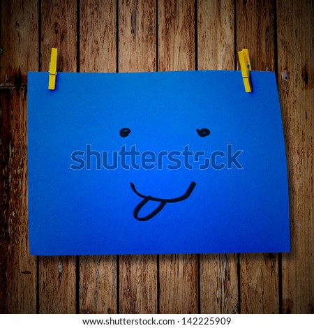 note paper and clothes peg on a wooden background with smile face