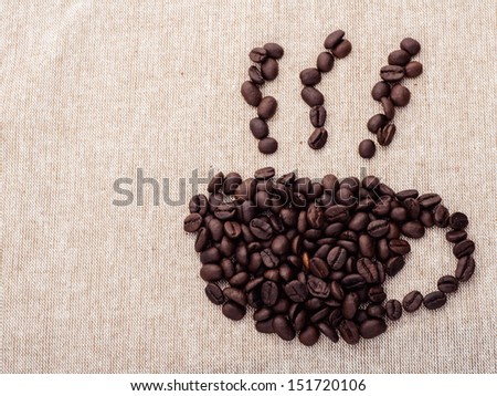 Coffee cup and smoke shape by coffee beans on brown fabric