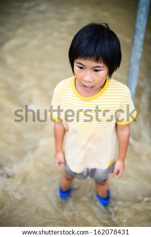 Happy Asian girl in blue boots,flood disaster.