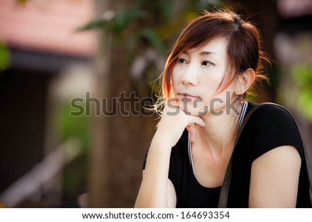 Beautiful Asian woman thinking in the park