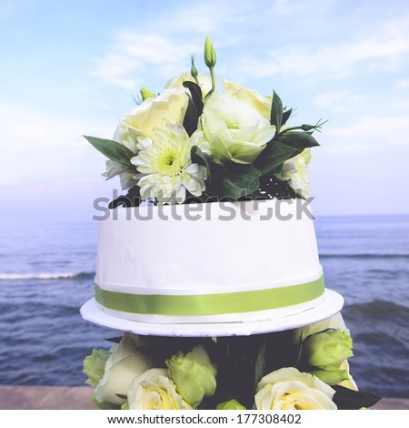 White and roses wedding cake by the beach