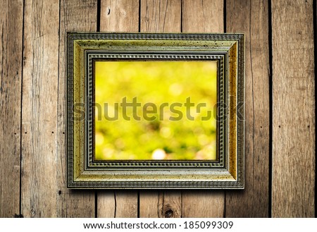 Old picture frame on vintage wood wall with yellow bokeh background.