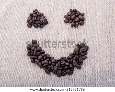 Smiling face by coffee beans on brown fabric
