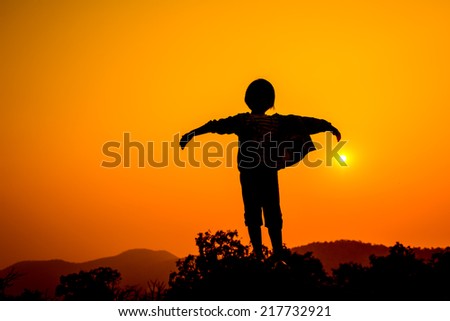 Girlraising her hands standing on top hill during sun set
